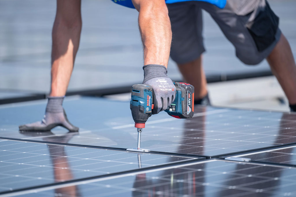 Handwerker beim Verschrauben eines Solarmoduls